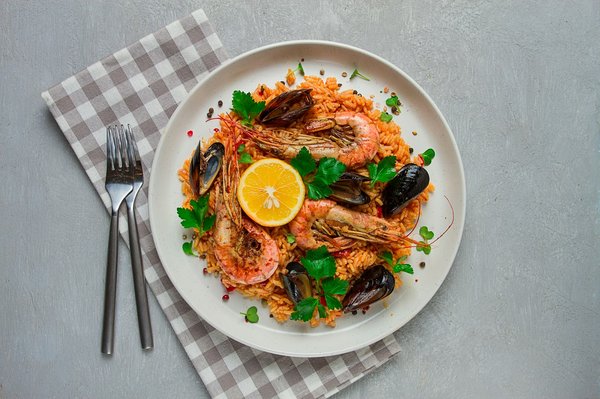 Quelle est la technique idéale pour cuisiner une paella aux fruits de mer sans brûler le riz?